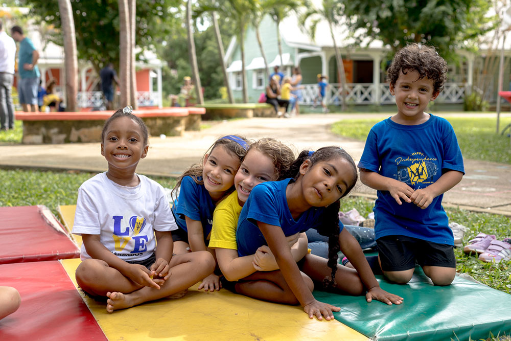 Happy group of elementary pupils sitting together outside