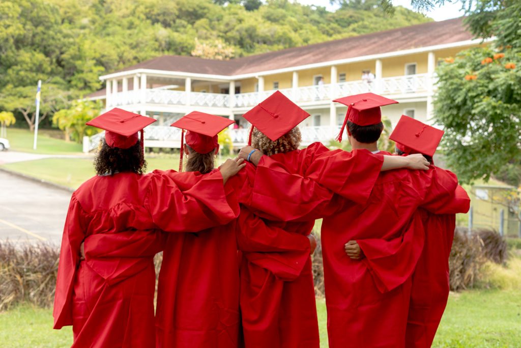 Secondary graduates standing arm in arm looking at the Providence campus