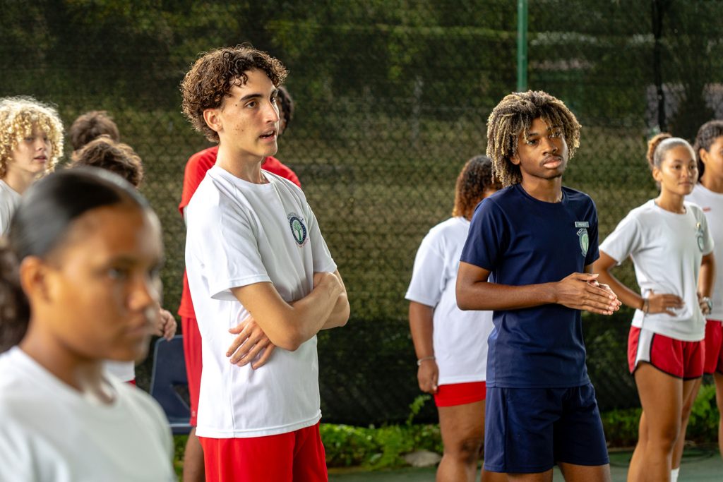 Group of secondary pupils standing and listening in sports class