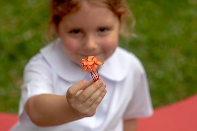 Young pupil holding out a flower outside